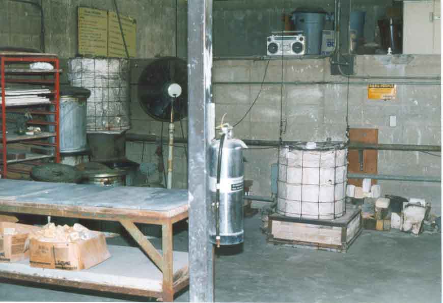 Raku kiln with surrounding area including fan, slate table, reduction containers, and fire extinguisher